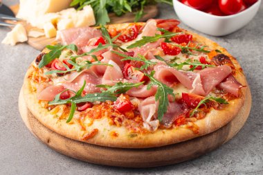 Prosciutto, jambon, roka, domates, pesto, peynir ve parmesanlı pizza. İtalyan mutfağı. 
