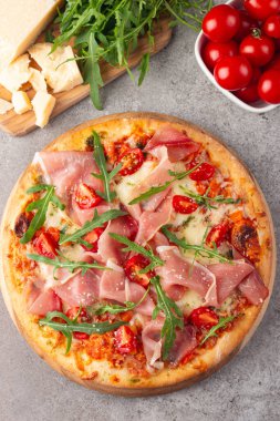 Prosciutto, jambon, roka, domates, pesto, peynir ve parmesanlı pizza. İtalyan mutfağı. 