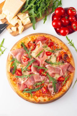 Prosciutto, jambon, roka, domates, pesto, peynir ve parmesanlı pizza. İtalyan mutfağı. 