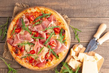 Prosciutto, jambon, roka, domates, pesto, peynir ve parmesanlı pizza. İtalyan mutfağı. 
