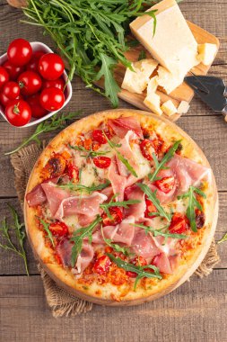 Prosciutto, jambon, roka, domates, pesto, peynir ve parmesanlı pizza. İtalyan mutfağı. 