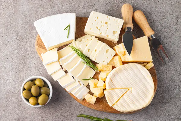 Çeşitli peynirler ve zeytinlerle ahşap tahta. Krem peynir. Camembert peyniri. Parmesan, feta, mavi peynir. İtalyan, Fransız peyniri.