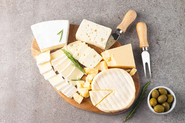 Çeşitli peynirler ve zeytinlerle ahşap tahta. Krem peynir. Camembert peyniri. Parmesan, feta, mavi peynir. İtalyan, Fransız peyniri.