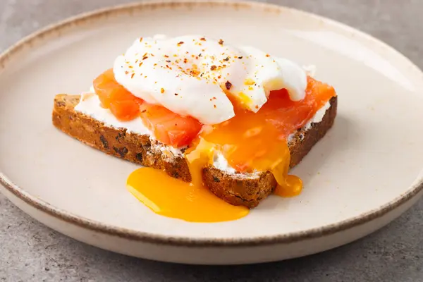 Poached egg on salmon and cheese toast. Breakfast food concept. Open sandwich.