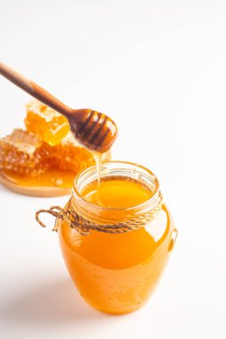 Honey dripping from a wooden honey dipper on white background. Healthy organic food concept. 