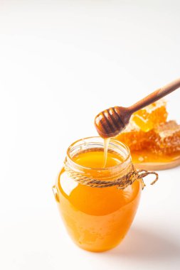 Honey dripping from a wooden honey dipper on white background. Healthy organic food concept. 