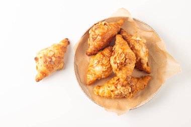 Tabağında badem olan taze pişmiş kruvasan.