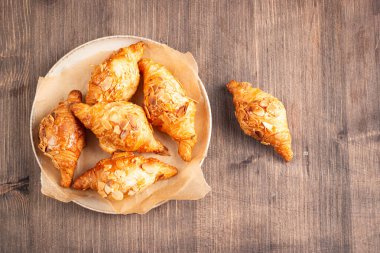 Tabağında badem olan taze pişmiş kruvasan.