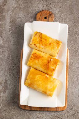 Süzme peynirle doldurulmuş ince krepler ekşi krema ve siyah frenk üzümü reçeli ile servis edilir. Fransız krepleri. 