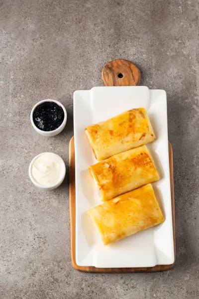 Süzme peynirle doldurulmuş ince krepler ekşi krema ve siyah frenk üzümü reçeli ile servis edilir. Fransız krepleri. 