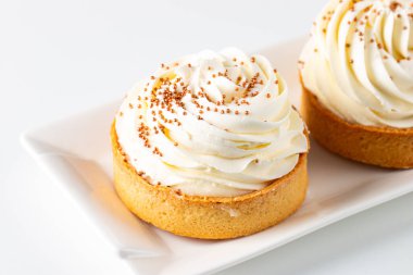 Krem şantili limonlu turtalar, beyaz arka planda çikolata parçaları.