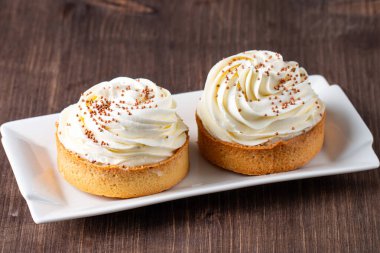 Krem şantili limonlu turtalar, beyaz arka planda çikolata parçaları.