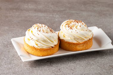 Krem şantili limonlu turtalar, beyaz arka planda çikolata parçaları.