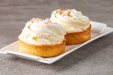 Krem şantili limonlu turtalar, beyaz arka planda çikolata parçaları.