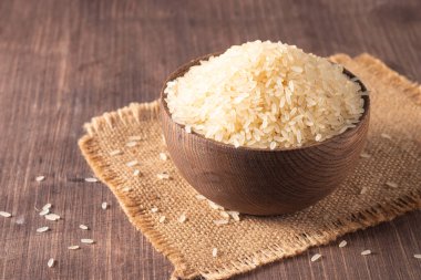 Tahta bir kasede pişmemiş beyaz pirinç. Sağlıklı gevrek kavramı.