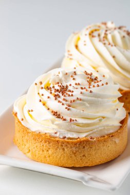 Krem şantili limonlu turtalar, beyaz arka planda çikolata parçaları.