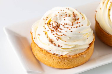 Krem şantili limonlu turtalar, beyaz arka planda çikolata parçaları.