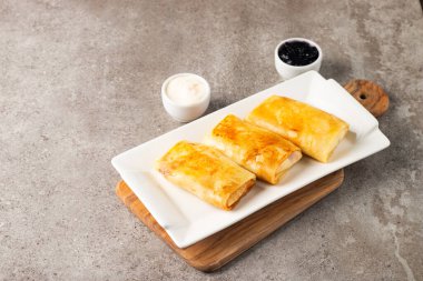 Süzme peynirle doldurulmuş ince krepler ekşi krema ve siyah frenk üzümü reçeli ile servis edilir. Fransız krepleri. 