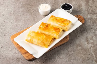 Süzme peynirle doldurulmuş ince krepler ekşi krema ve siyah frenk üzümü reçeli ile servis edilir. Fransız krepleri. 