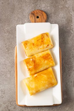 Süzme peynirle doldurulmuş ince krepler ekşi krema ve siyah frenk üzümü reçeli ile servis edilir. Fransız krepleri. 