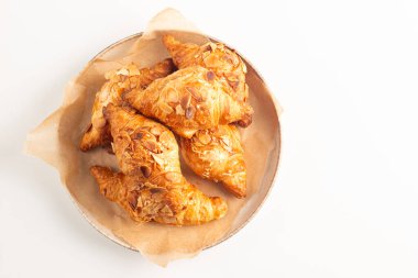 Tabağında badem olan taze pişmiş kruvasan.