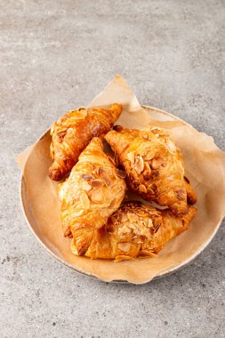 Tabağında badem olan taze pişmiş kruvasan.