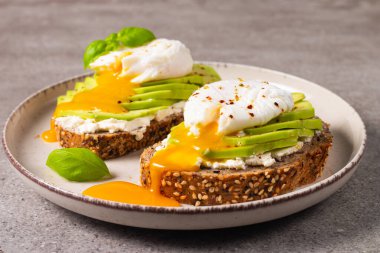 Avokado, krem peynirli tost çavdar ekmeği ve haşlanmış yumurta. Sağlıklı kahvaltı konsepti için açık sandviç..