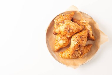 Tabağında badem olan taze pişmiş kruvasan.