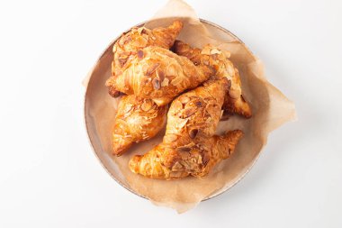 Tabağında badem olan taze pişmiş kruvasan.