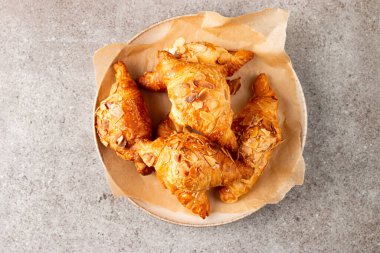 Tabağında badem olan taze pişmiş kruvasan.