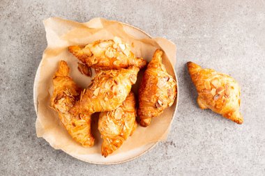 Tabağında badem olan taze pişmiş kruvasan.