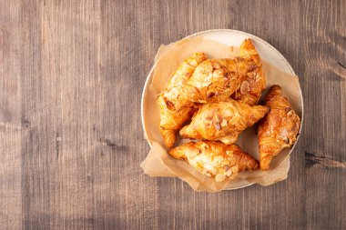 Tabağında badem olan taze pişmiş kruvasan.