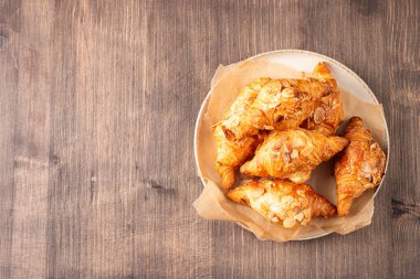 Tabağında badem olan taze pişmiş kruvasan.