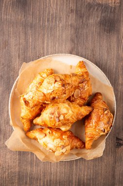 Tabağında badem olan taze pişmiş kruvasan.