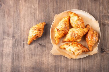 Tabağında badem olan taze pişmiş kruvasan.