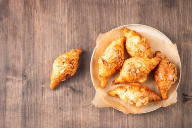 Tabağında badem olan taze pişmiş kruvasan.