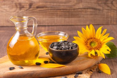 Geleneksel ahşap arka planda ayçiçeği yağı ve ayçiçeği tohumları. Organik ve ekolojik gıda konsepti. Sağlıklı yiyecekler ve yağlar.