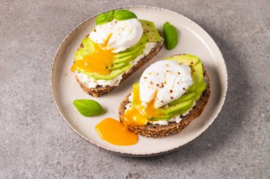 Avokado, krem peynirli tost çavdar ekmeği ve haşlanmış yumurta. Sağlıklı kahvaltı konsepti için açık sandviç.