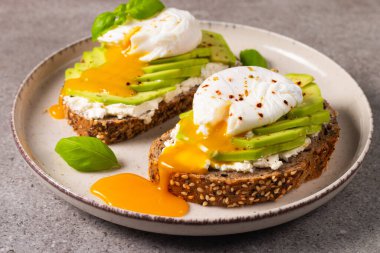 Avokado, krem peynirli tost çavdar ekmeği ve haşlanmış yumurta. Sağlıklı kahvaltı konsepti için açık sandviç.