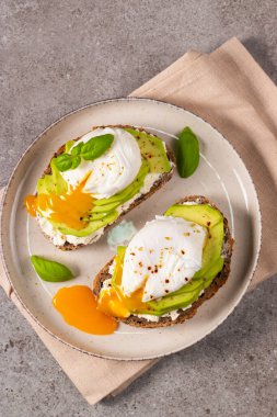 Avokado, krem peynirli tost çavdar ekmeği ve haşlanmış yumurta. Sağlıklı kahvaltı konsepti için açık sandviç.