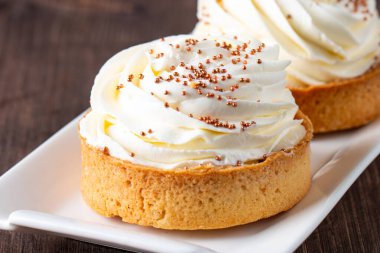 Krem şantili limonlu turtalar, beyaz arka planda çikolata parçaları.