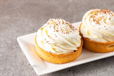 Krem şantili limonlu turtalar, beyaz arka planda çikolata parçaları.