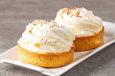 Krem şantili limonlu turtalar, beyaz arka planda çikolata parçaları.