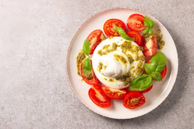 Çeri domatesli Burrata peynirli Caprese salatası, zeytin yağı, pesto ve baharat. Taze gıda konsepti. 