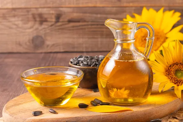 Geleneksel ahşap arka planda ayçiçeği yağı ve ayçiçeği tohumları. Organik ve ekolojik gıda konsepti. Sağlıklı yiyecekler ve yağlar.