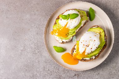 Avokado, krem peynirli tost çavdar ekmeği ve haşlanmış yumurta. Sağlıklı kahvaltı konsepti için açık sandviç.