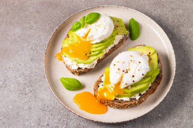 Avokado, krem peynirli tost çavdar ekmeği ve haşlanmış yumurta. Sağlıklı kahvaltı konsepti için açık sandviç.