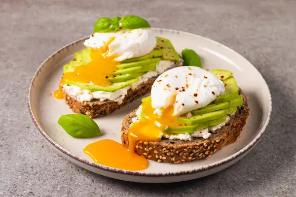 Avokado, krem peynirli tost çavdar ekmeği ve haşlanmış yumurta. Sağlıklı kahvaltı konsepti için açık sandviç.