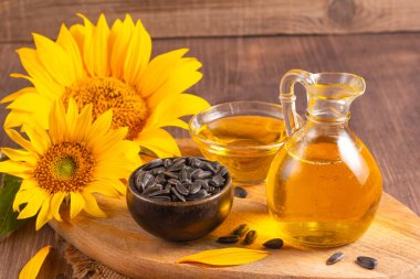 Geleneksel ahşap arka planda ayçiçeği yağı ve ayçiçeği tohumları. Organik ve ekolojik gıda konsepti. Sağlıklı yiyecekler ve yağlar.