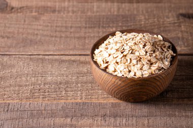 Ahşap bir arka planda tahta bir kasede çiğ yulaf. Organik gıda konsepti. 